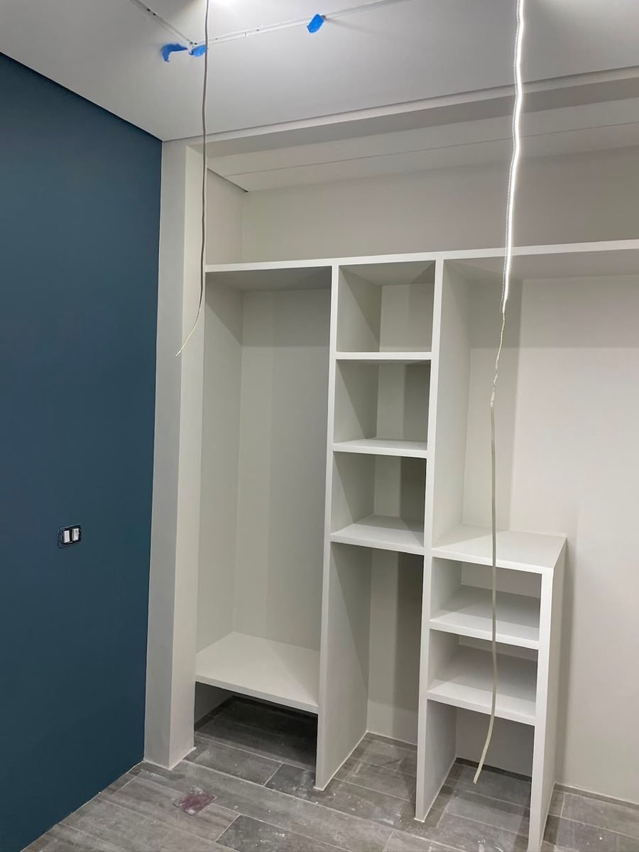 Closet depois: parede pintada em tom petróleo com marcenaria finalizada