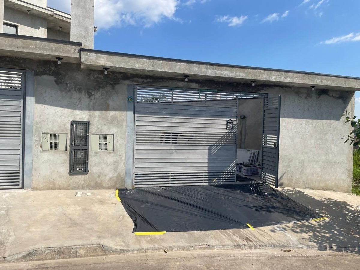 Fachada com portão antes: reboco cinza sem pintura