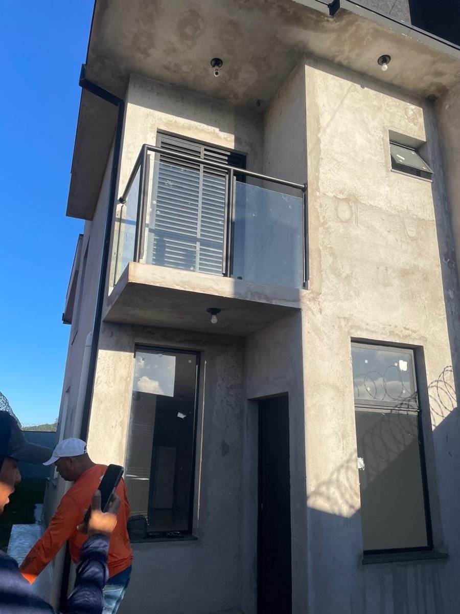 Sobrado antes: fachada em reboco cinza sem pintura, obra em fase de acabamento